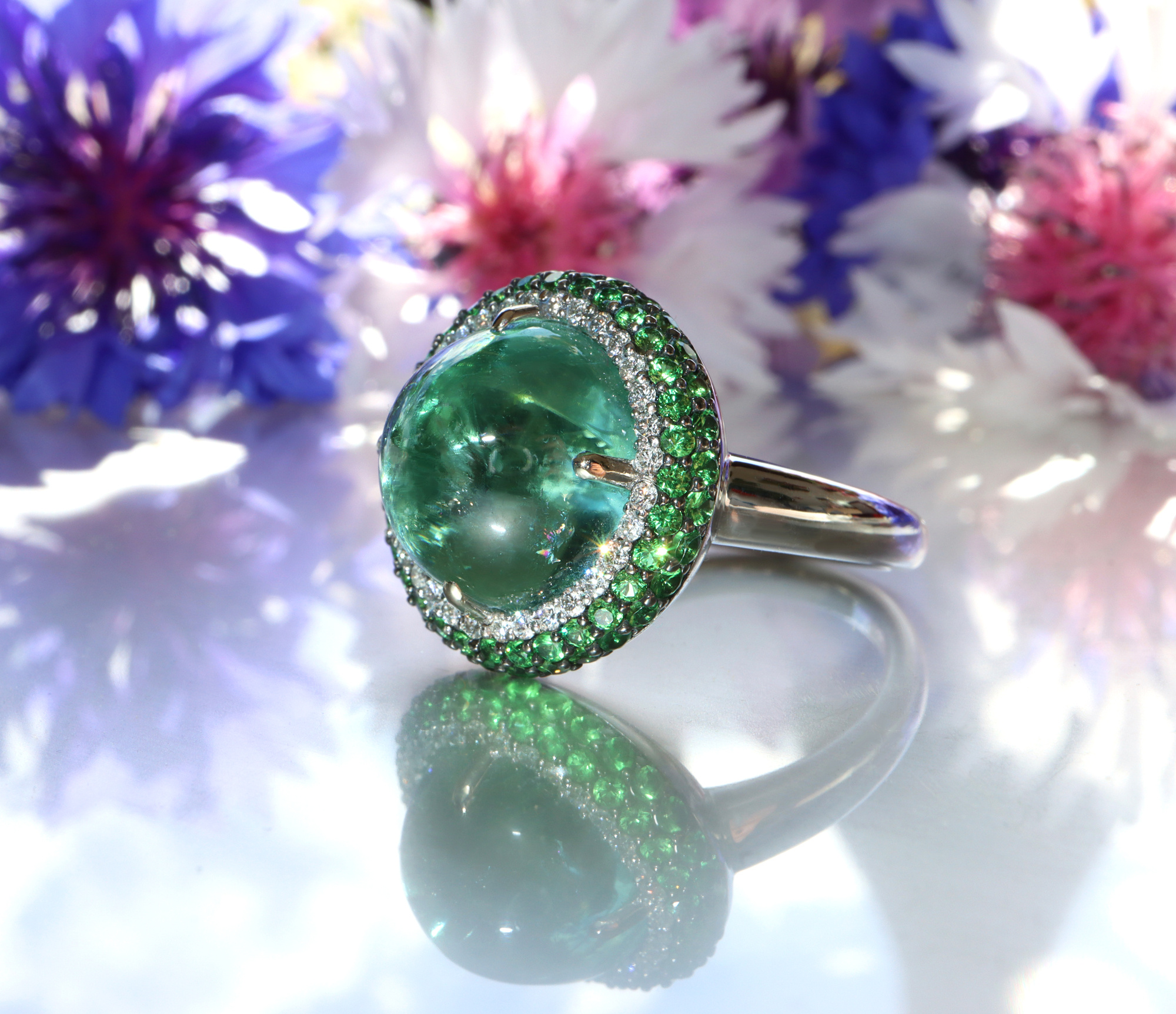 Minz-Turmalin-Ring mit Tsavorite und Brillanten, Detailaufnahme, weißgold, Blumen im Hintergrund