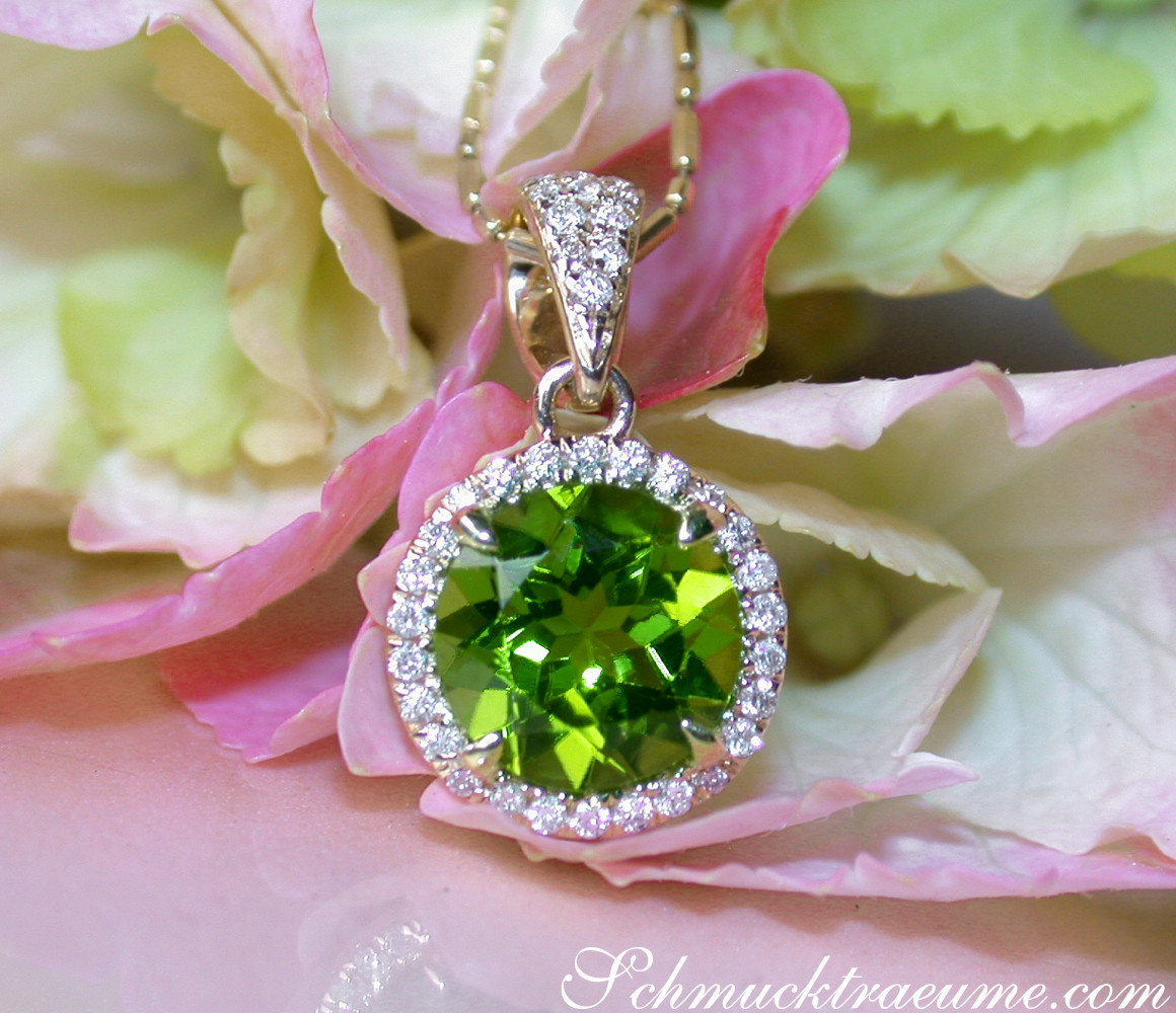 Peridot-Anhänger mit Diamanten, Gelbgold 585, Detailaufnahme mit Blüte im Hintergrund.