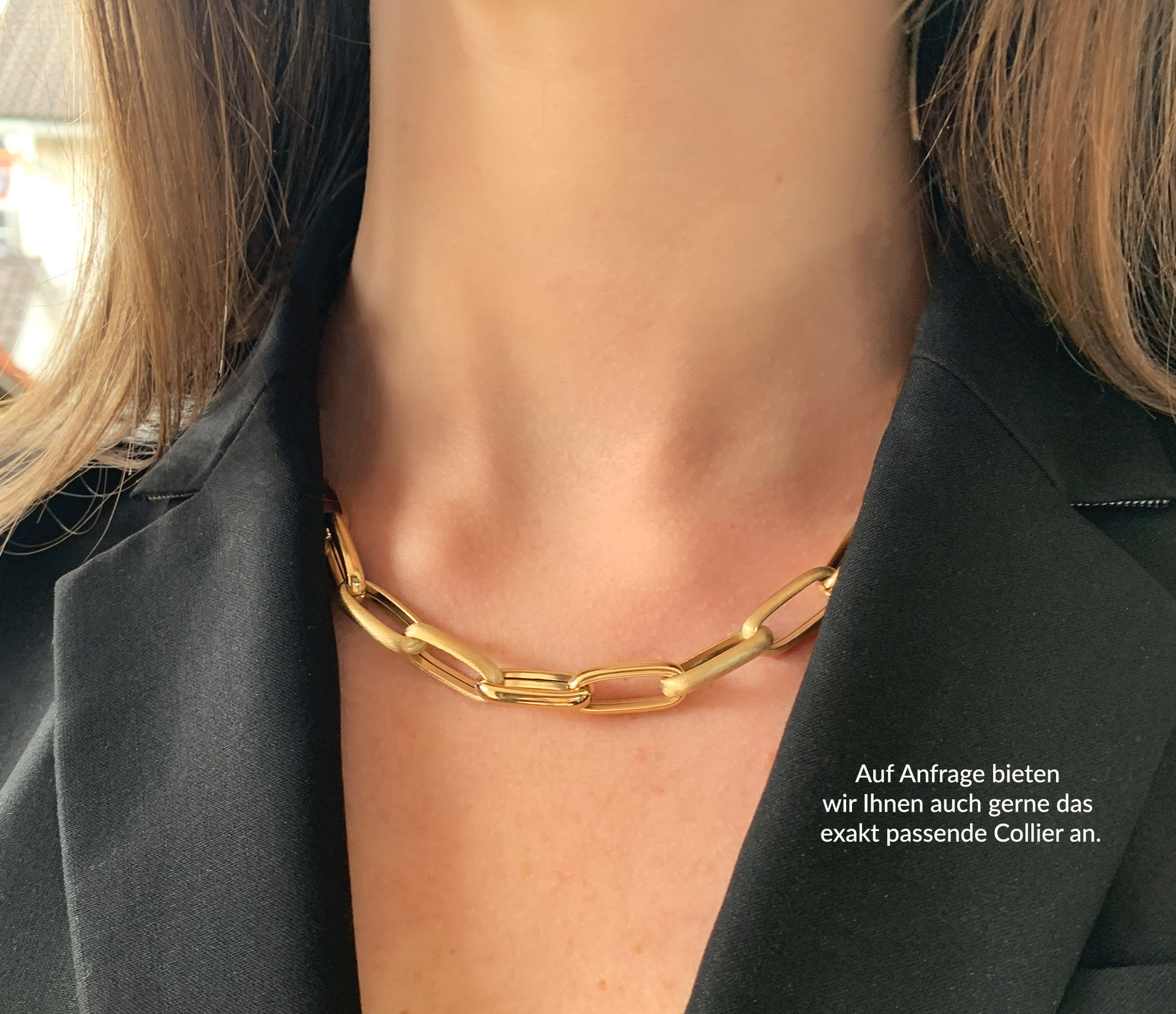 Goldene Paperclip-Armband mit glänzender und satiniertem Finish, getragen unter schwarzer Jacke.