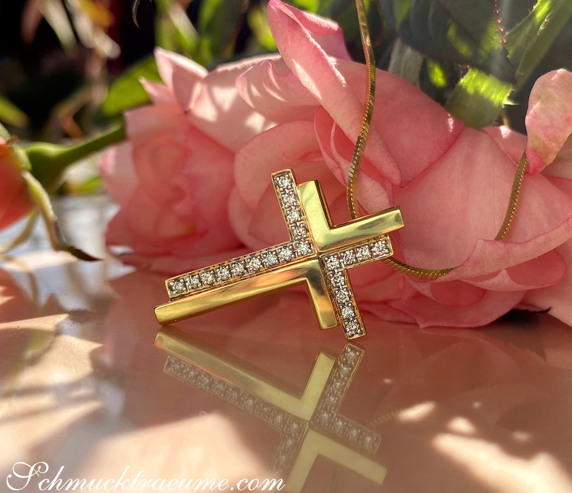 Goldener Kreuzanhänger „Duett“ mit Diamanten, rosa Blume im Hintergrund