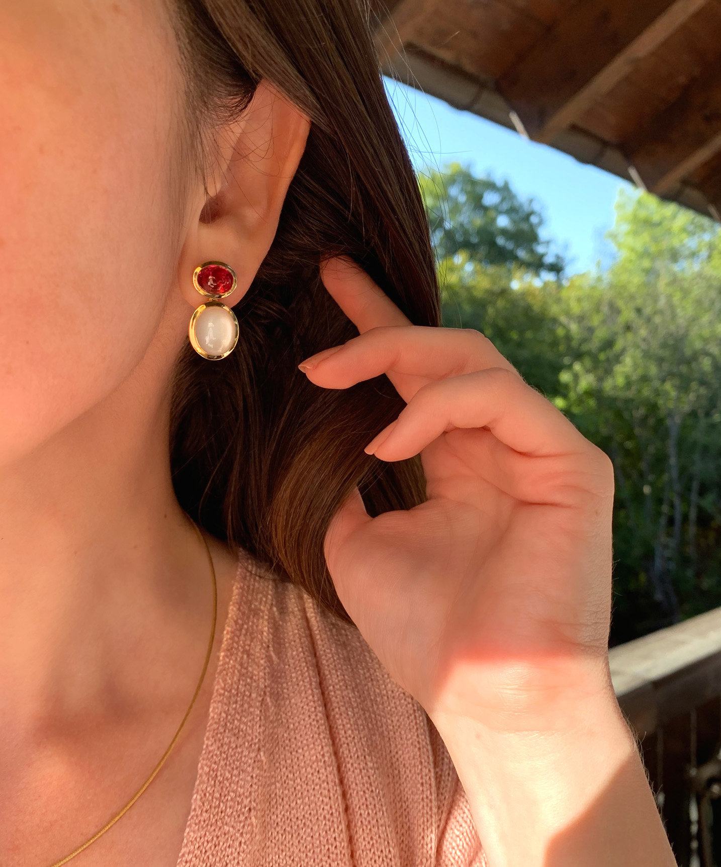 Goldene Ohrringe mit Rubellit und Mondstein, Detailaufnahme bei Tageslicht