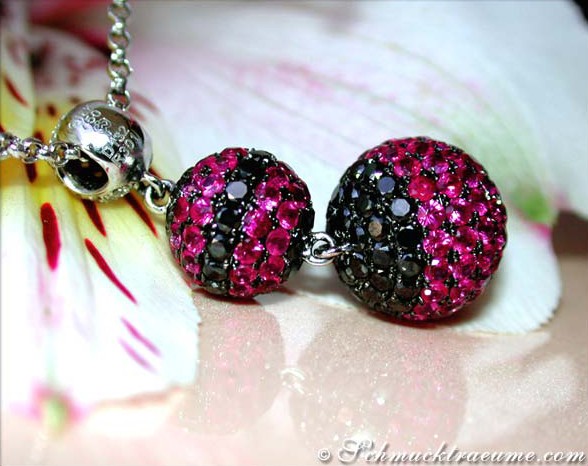 Schmuckkette mit Rubinen, Brillanten & schwarzen Diamanten, detailreich auf Blüte.