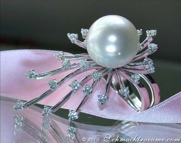 Weißgoldring mit Südseeperle und Strahlenbrillanten, detailreich, auf rosa Satin liegend.