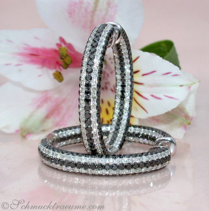 Schwarze und weiße Diamant-Creolen auf Blumenhintergrund