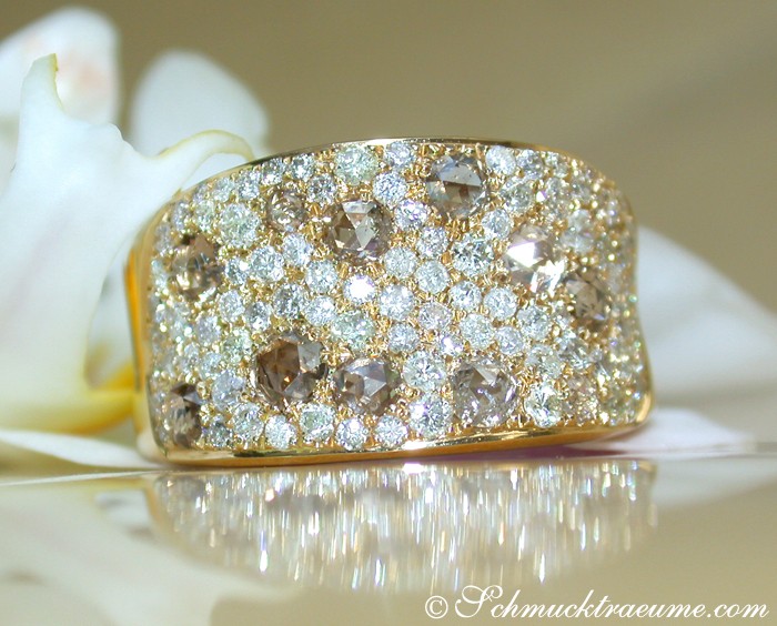 Goldener Brillant-Ring mit Diamanten und Brauntönen, Detailaufnahme, elegant auf Blüte platziert.
