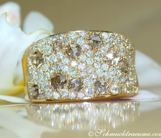 Goldener Brillant-Ring mit Diamanten und Brauntönen, Detailaufnahme, elegant auf Blüte platziert.