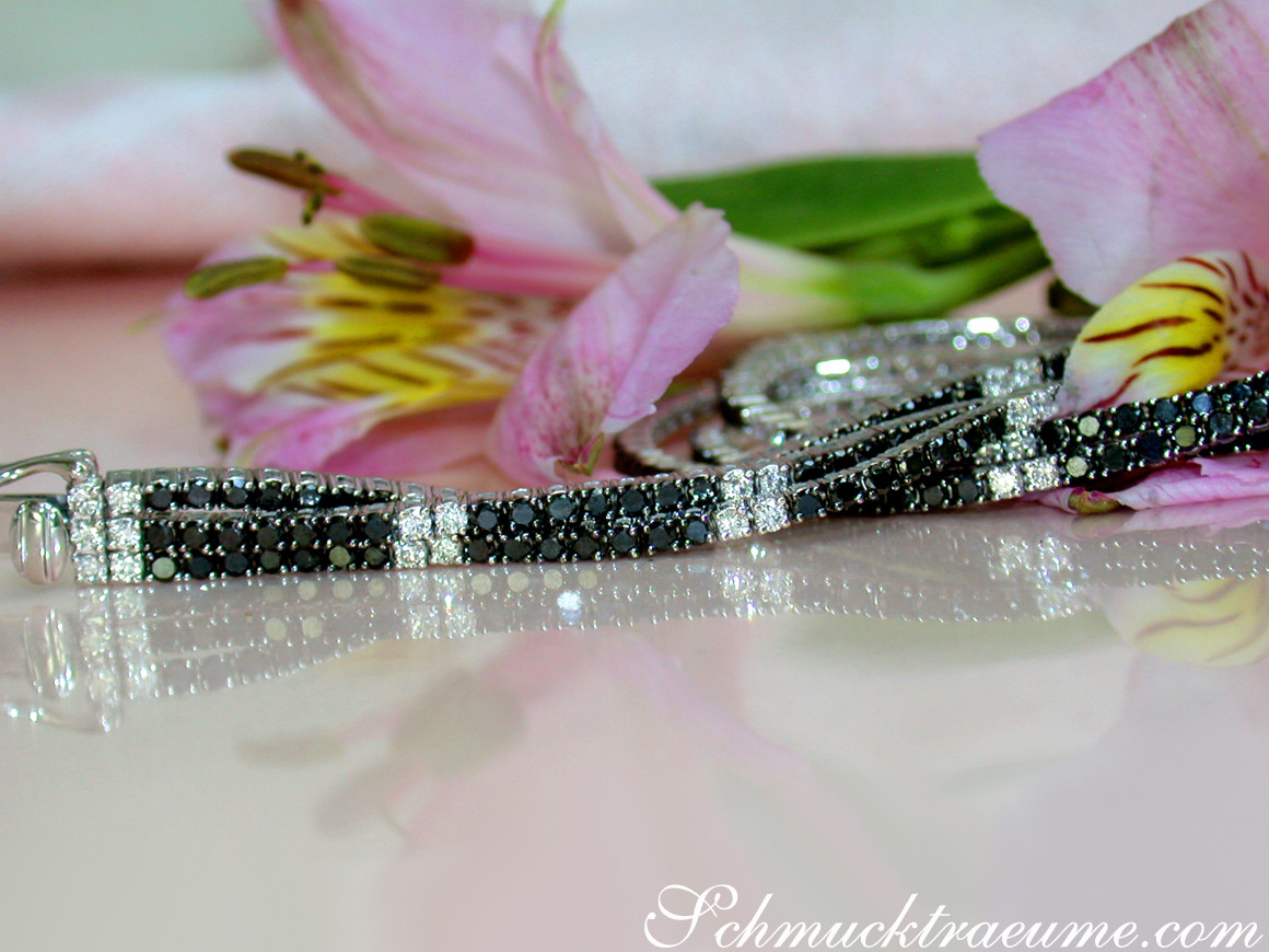 Dreireihiges Tennisarmband mit schwarzen und weißen Diamanten, detailreich, elegant auf glänzender Oberfläche.