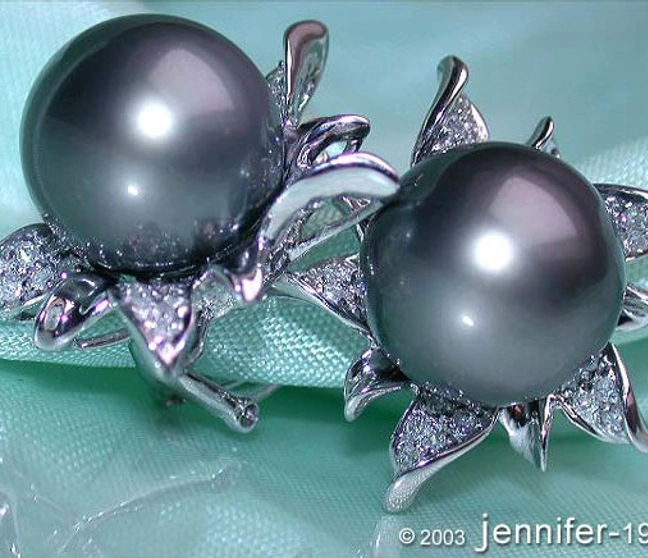Tahitiperlen-Ohrringe im Blüten-Design mit Diamanten, elegant auf Blattgras. Tahitiperlen-Ohrringe im Blüten-Design mit Diamanten, elegant auf Blattgras.