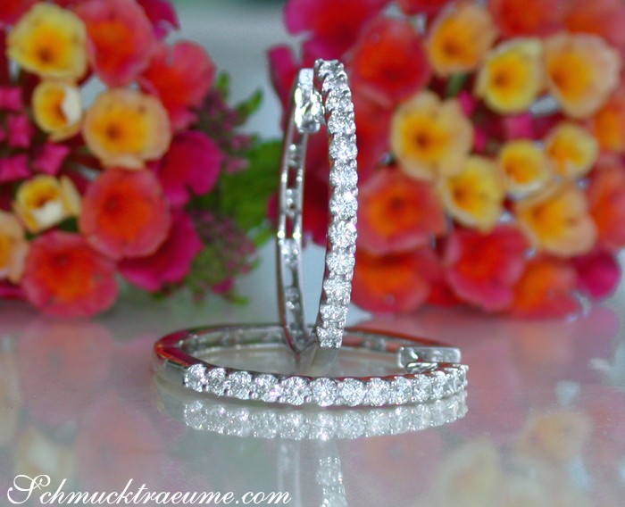 Klassische Diamant-Creolen in Weißgold 750, detailreich, elegant, mit Blumen im Hintergrund