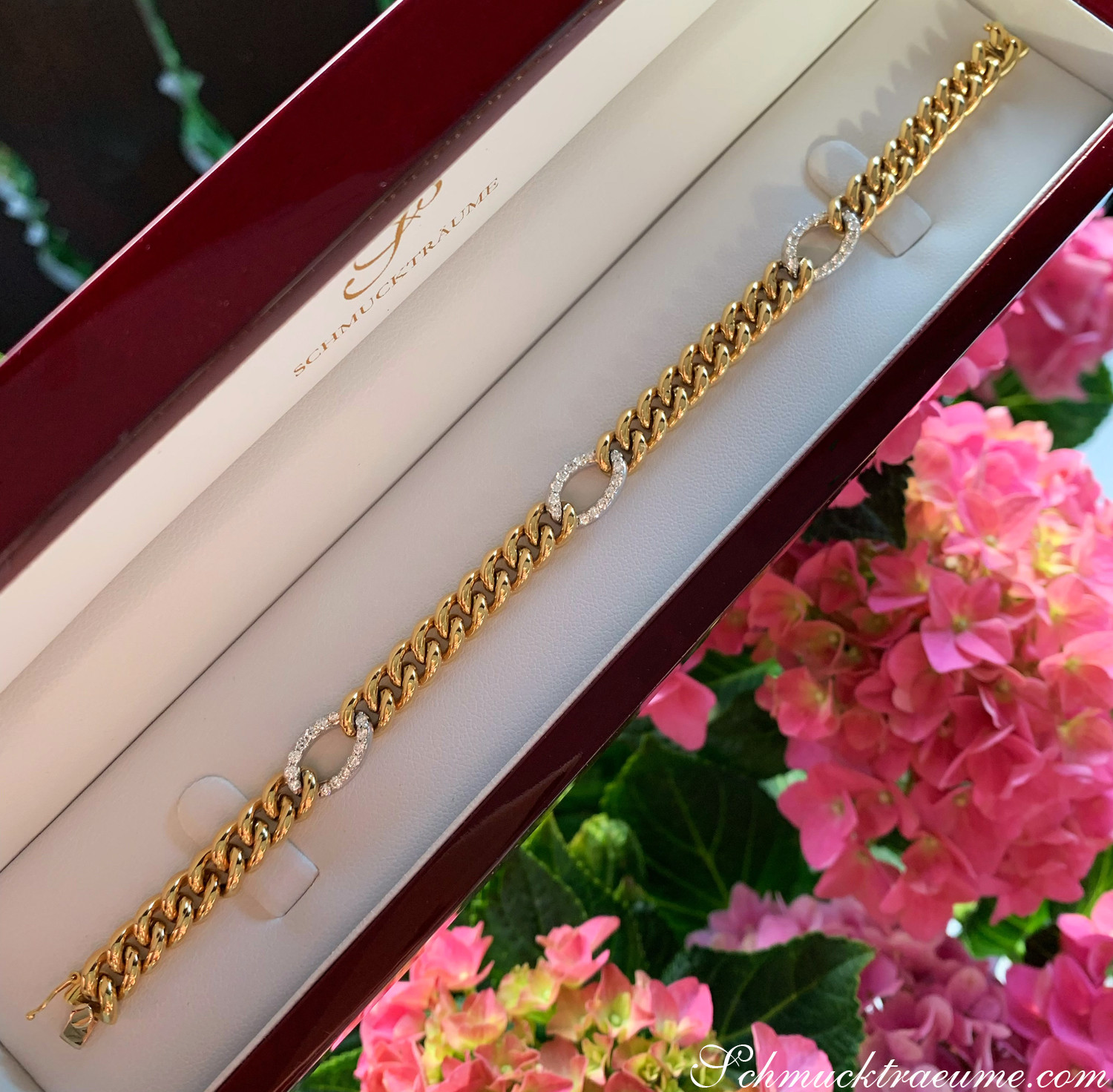 Goldene Panzerarmband mit Brillanten in Box, Blumen im Hintergrund
