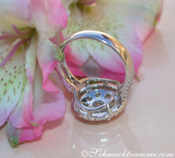 Halo-Design Brillantenring in Weißgold, Detailaufnahme mit Blume im Hintergrund