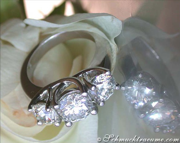 Detailaufnahme eines Luxus-Diamantrings mit drei Solitären, getragen auf einer Blume