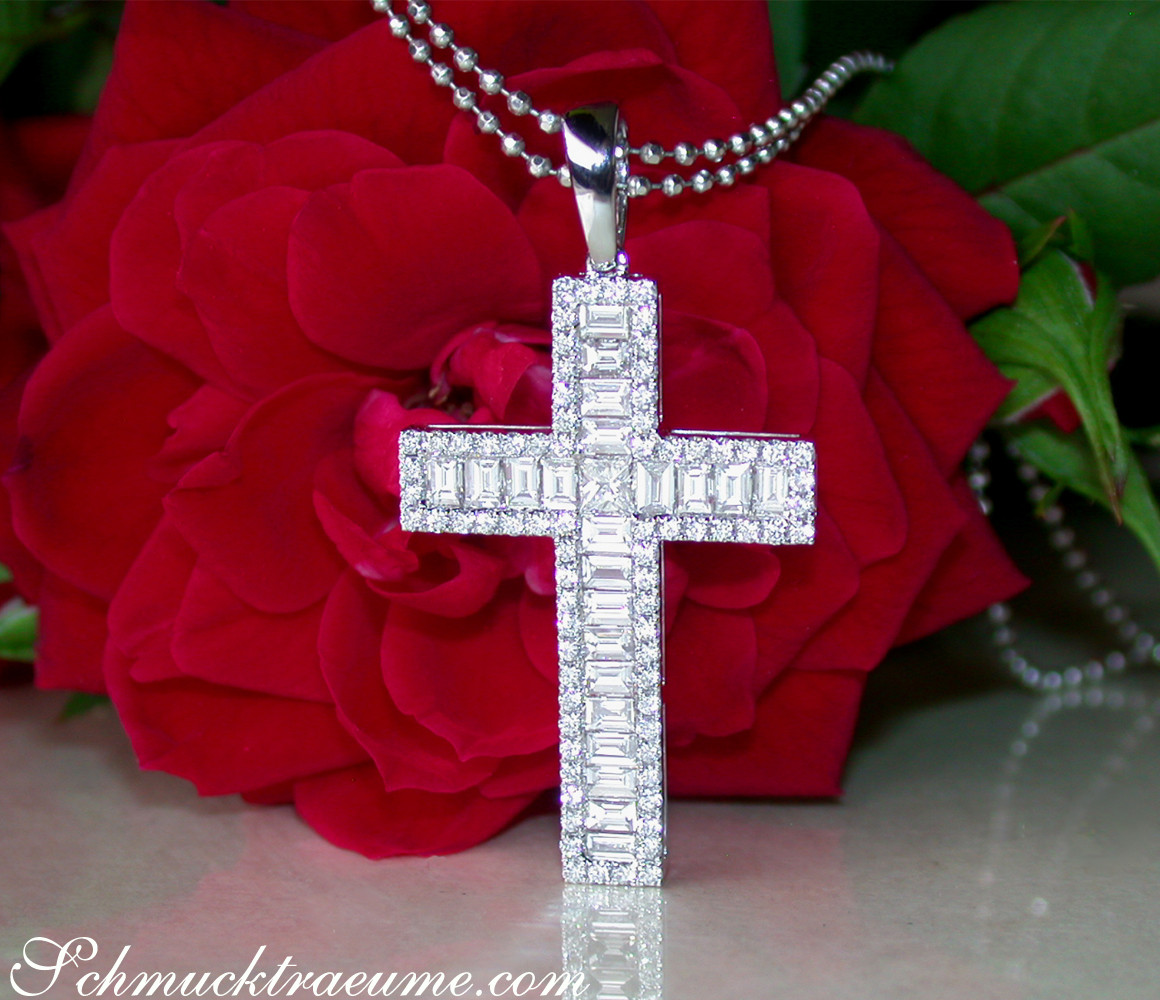 Diamantkreuzanhänger mit Baguette-Diamanten auf Kette, vor roter Rose.