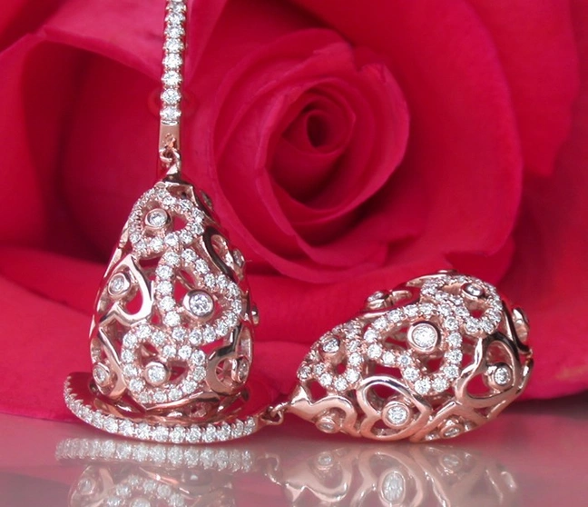 Herzformige Ohrringe aus Roségold mit Brillanten vor Rosenblüte Herzformige Ohrringe aus Roségold mit Brillanten vor Rosenblüte