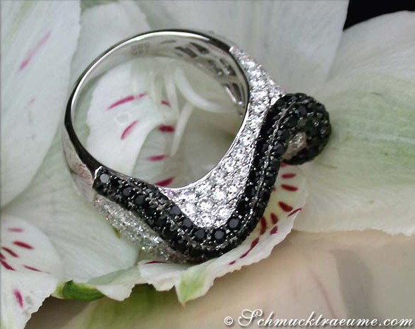 Schwarz-Weiß-Diamant-Ring im Wellendesign auf Orchideenblüte getragen