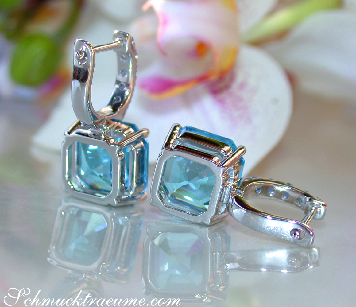 Blautopas-Ohrringe mit Saphiren in Weißgold, Detailaufnahme, Orchidee im Hintergrund