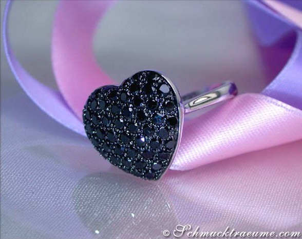 Herzring mit schwarzen Diamanten auf weißem Hintergrund, Detailaufnahme, eleganter Schmuck.