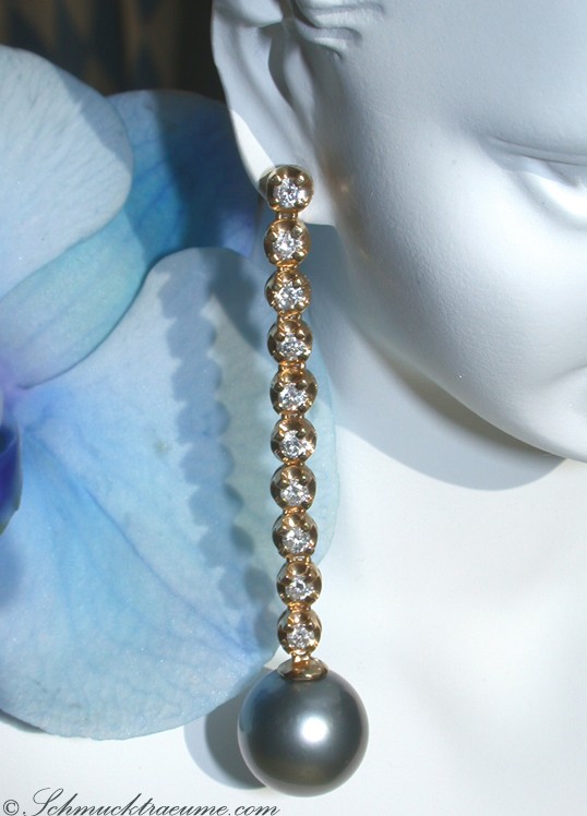 Goldene Perlenohrringe mit Diamanten, lang gestreckt, auf weißem Mannequin, blauer Hintergrund.