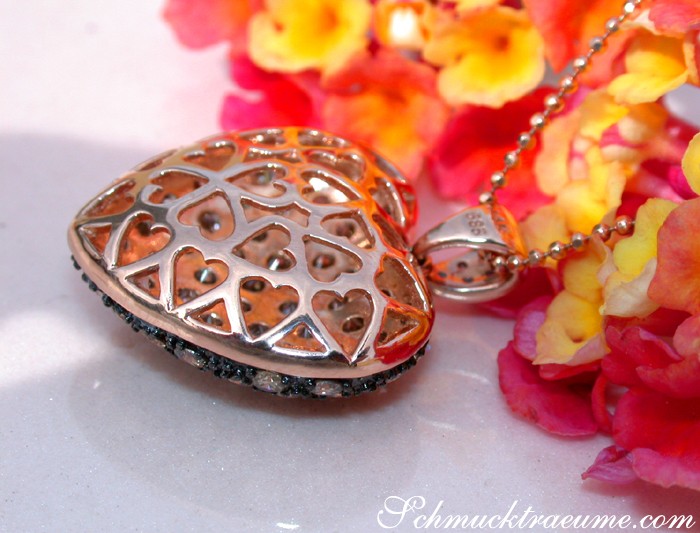 Herz-Anhänger aus Roségold mit natürlichen Brauntönen und funkelnden Steinen, detailreiches Design, umgeben von Blumen.