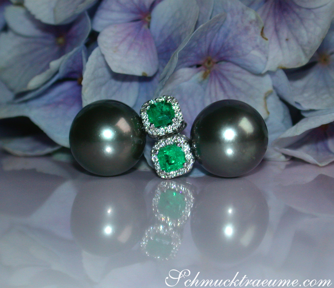 Tahitiperlen-Ohrstecker mit Smaragd und Diamanten, vor blauen Hortensienblüten.