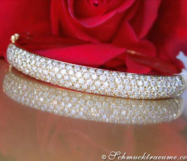 Gelbgold-Armreif mit Diamanten, klassischer Chic auf glänzender Oberfläche, Rosenblüte im Hintergrund Gelbgold-Armreif mit Diamanten, klassischer Chic auf glänzender Oberfläche, Rosenblüte im Hintergrund
