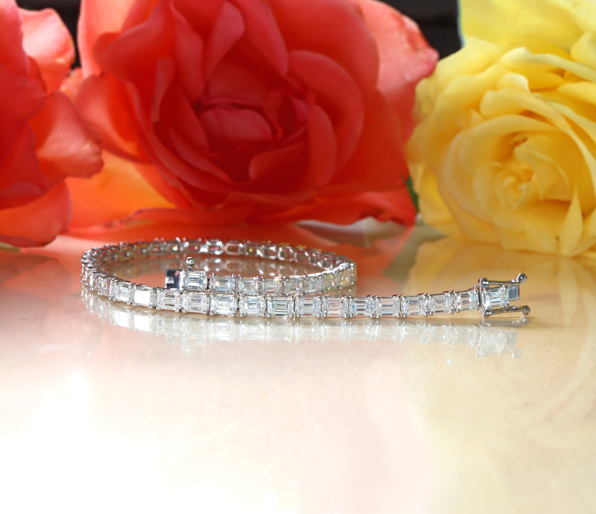 Weißgold-Armband mit Smaragdschliff-Diamanten vor Rosenblüten