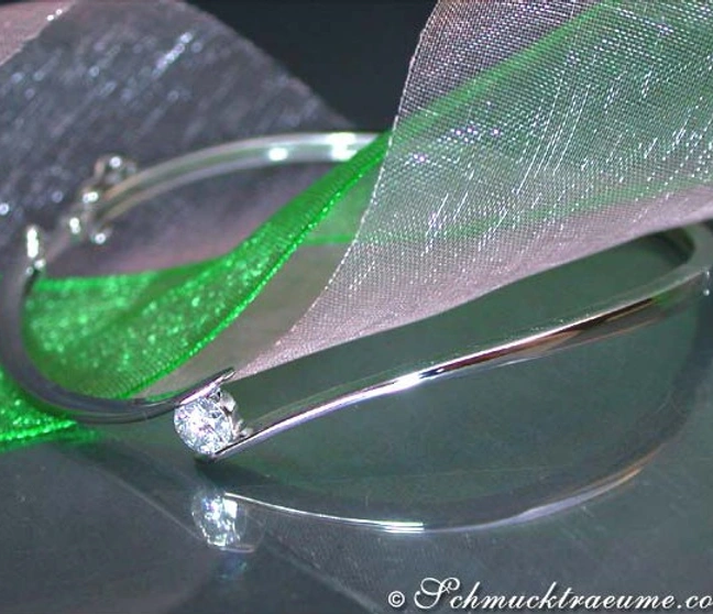 Silberner Armreif mit Brillant auf grünem Organza vor dunklem Hintergrund Silberner Armreif mit Brillant auf grünem Organza vor dunklem Hintergrund