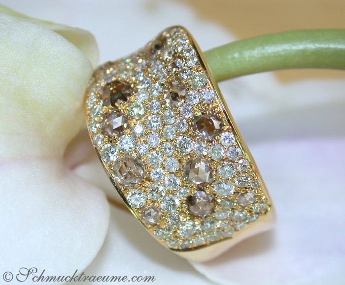 Goldener Ring mit weiß-braunen Brillanten auf Blume getragen