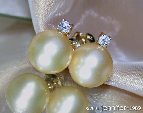 Goldene Südseeperlen Ohrstecker mit Diamanten, Detailaufnahme auf Satin, elegant und luxuriös