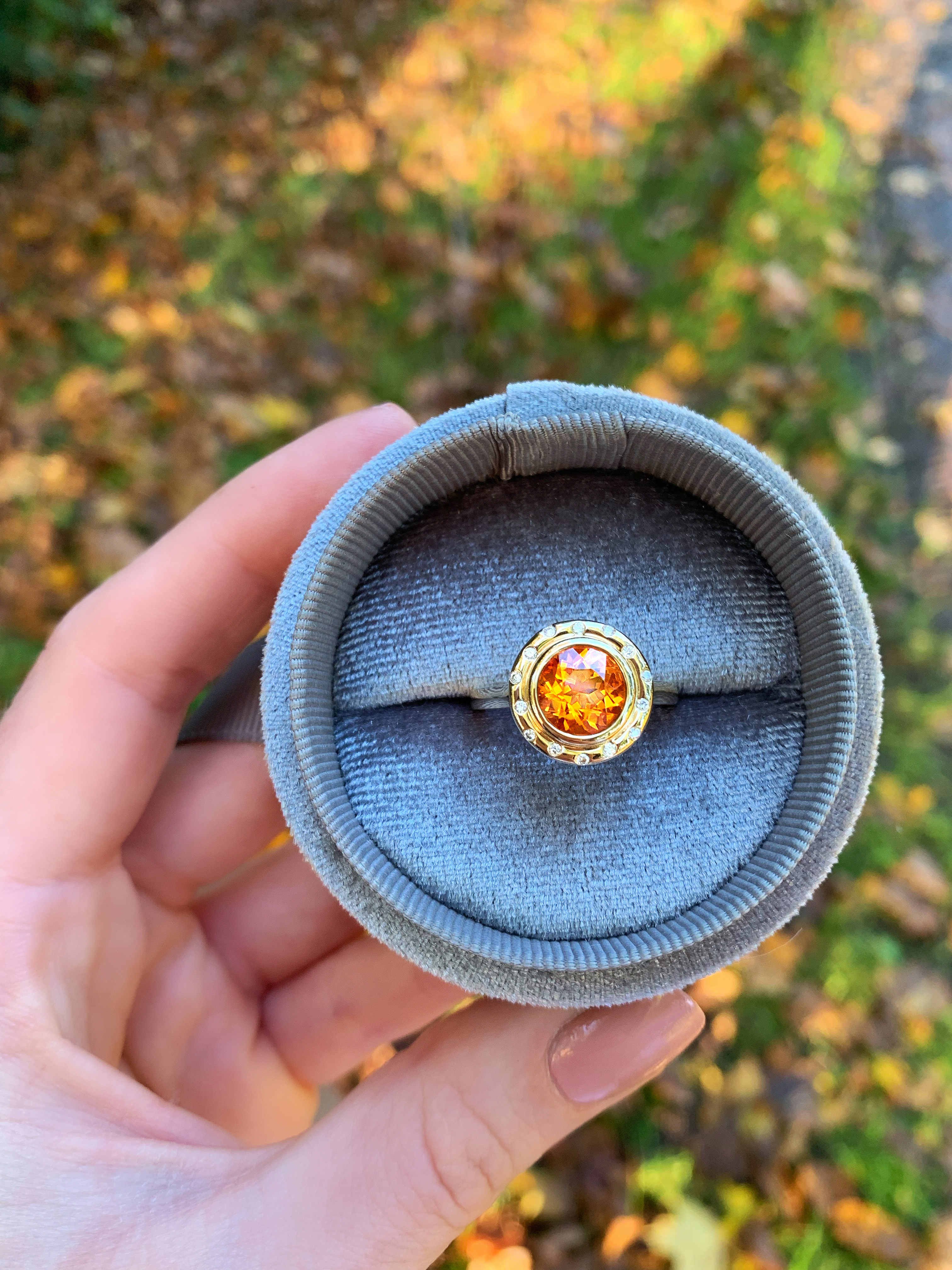 Hand hält Ring 'Orbit' mit Citrin und Brillanten im Samtkästchen
