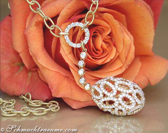 Goldene Halskette mit Brillantenkugel und Perlen, vor Rosenblüte präsentiert