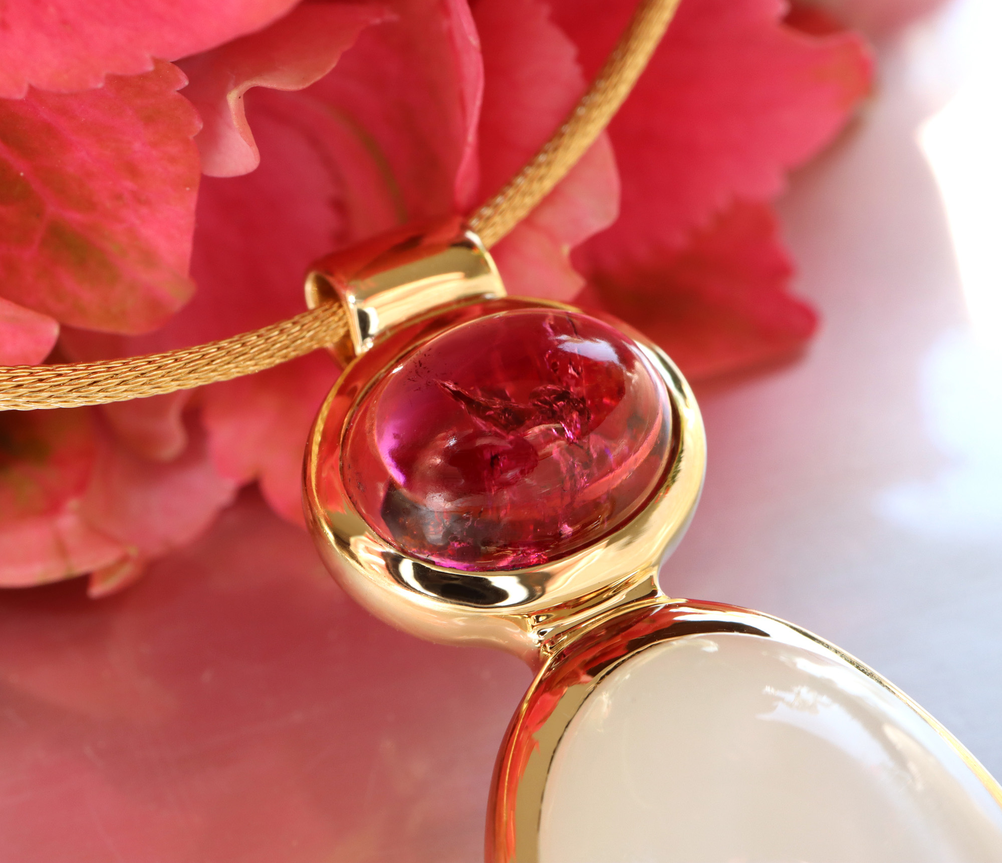 Goldene Rubellit-Halskette mit sanfter Linie und Farbverlauf, detailreiches Design, Rosenblüten im Hintergrund.