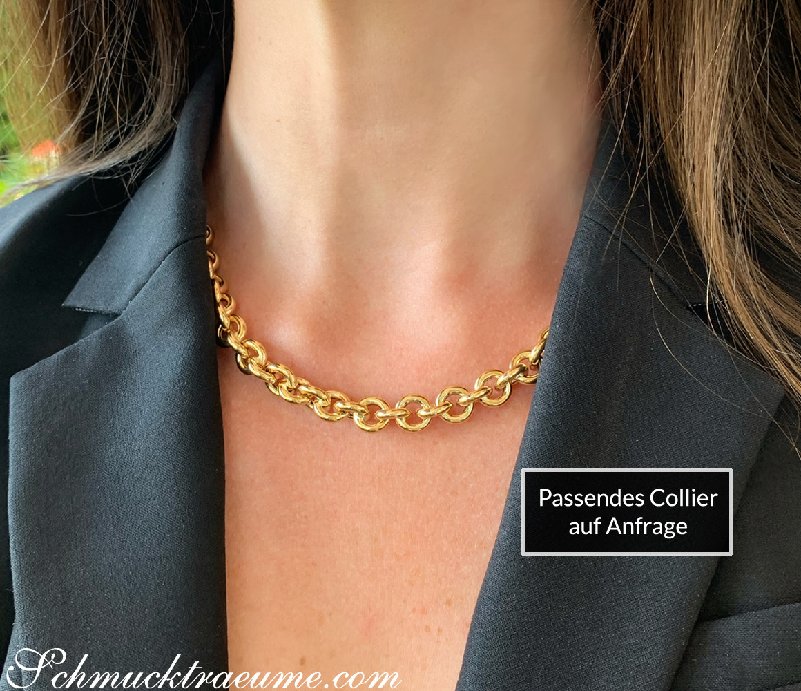 Goldarmband mit glänzenden Ringen, getragen unter grauem Blazer