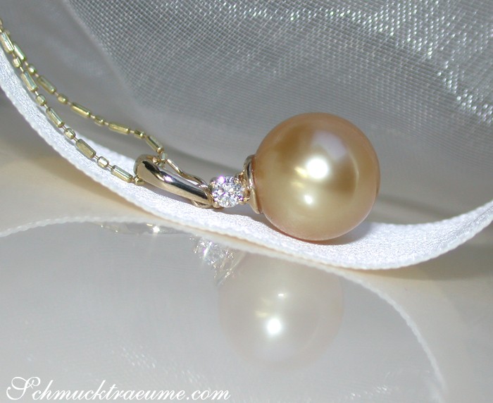 Goldener Südseeperlen-Anhänger mit Brillant, Detailaufnahme auf weißer Satinoberfläche