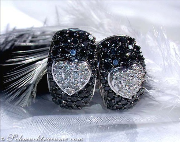 Schwarz-weiße Herz-Ohrstecker mit Diamanten, detailreiches Design, elegant auf Federhintergrund