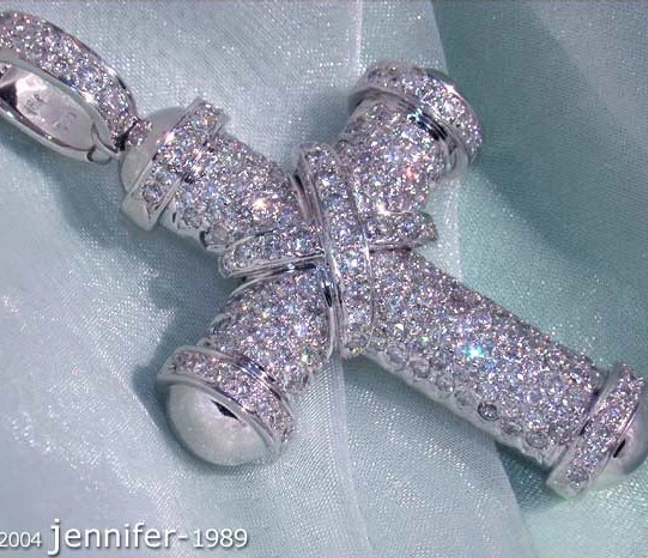 Weißgoldkreuzanhänger mit Diamanten, detailreich, auf blauem Stoff liegend Weißgoldkreuzanhänger mit Diamanten, detailreich, auf blauem Stoff liegend