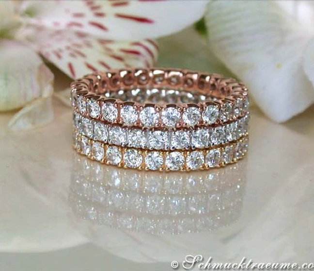 Ringe aus Weiß-, Rosé & Gelbgold 585 mit Diamanten, elegant gestapelt, Blüten im Hintergrund Ringe aus Weiß-, Rosé & Gelbgold 585 mit Diamanten, elegant gestapelt, Blüten im Hintergrund