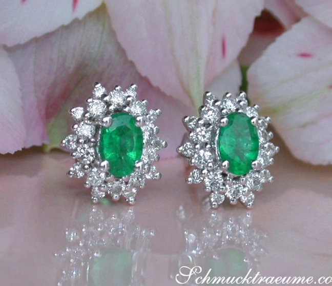 Smaragd-Ohrstecker mit Diamanten in Weißgold, auf Blütenblättern liegend. Smaragd-Ohrstecker mit Diamanten in Weißgold, auf Blütenblättern liegend.
