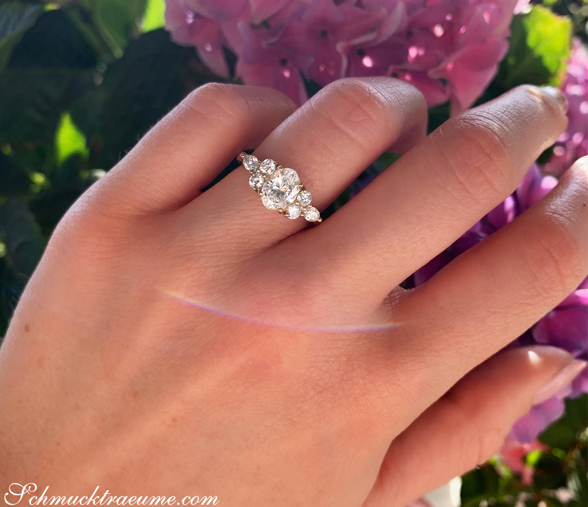 Goldener Diamant-Solitär-Ring mit Oval- und Marquise-Diamanten vor lila Blüten