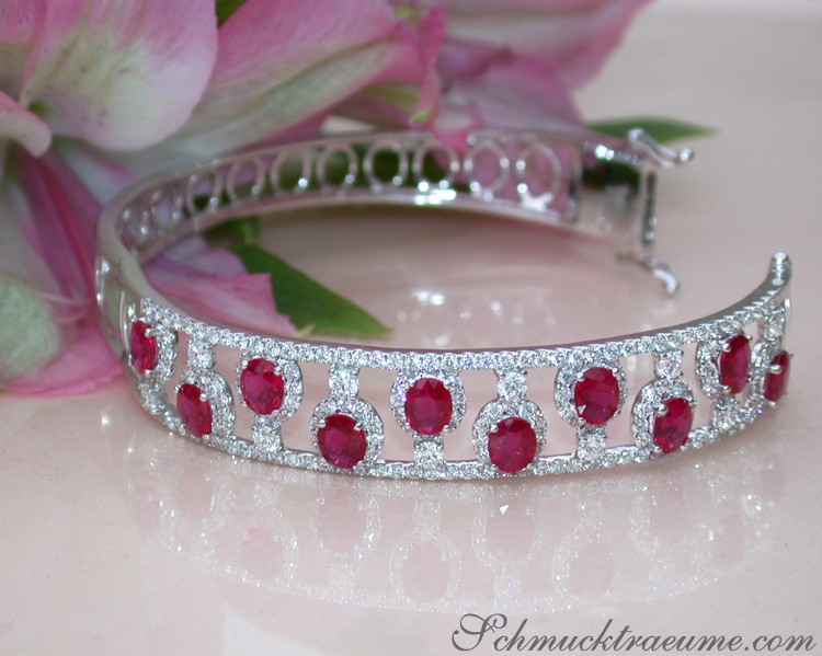 Luxuriöser Rubin-Armreif mit Brillanten in Weißgold, detailreich, blühende Blüten im Hintergrund