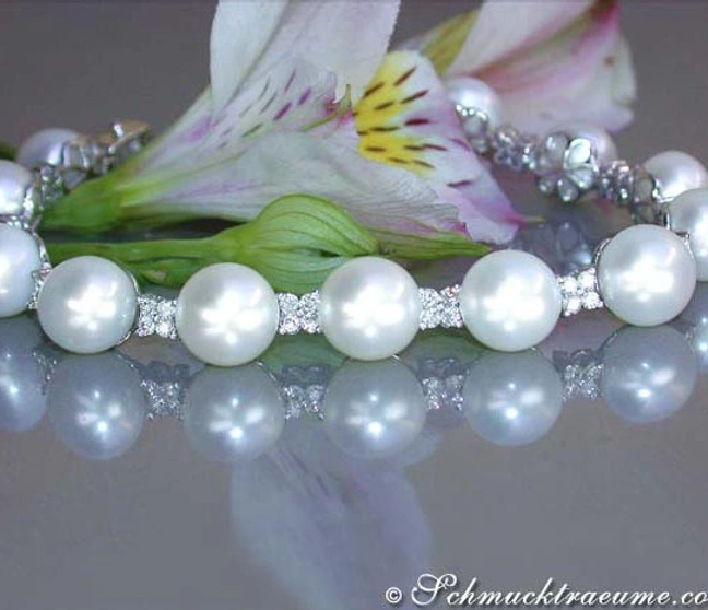 Perlenarmband mit Diamanten auf glänzender Oberfläche, Blume im Hintergrund Perlenarmband mit Diamanten auf glänzender Oberfläche, Blume im Hintergrund
