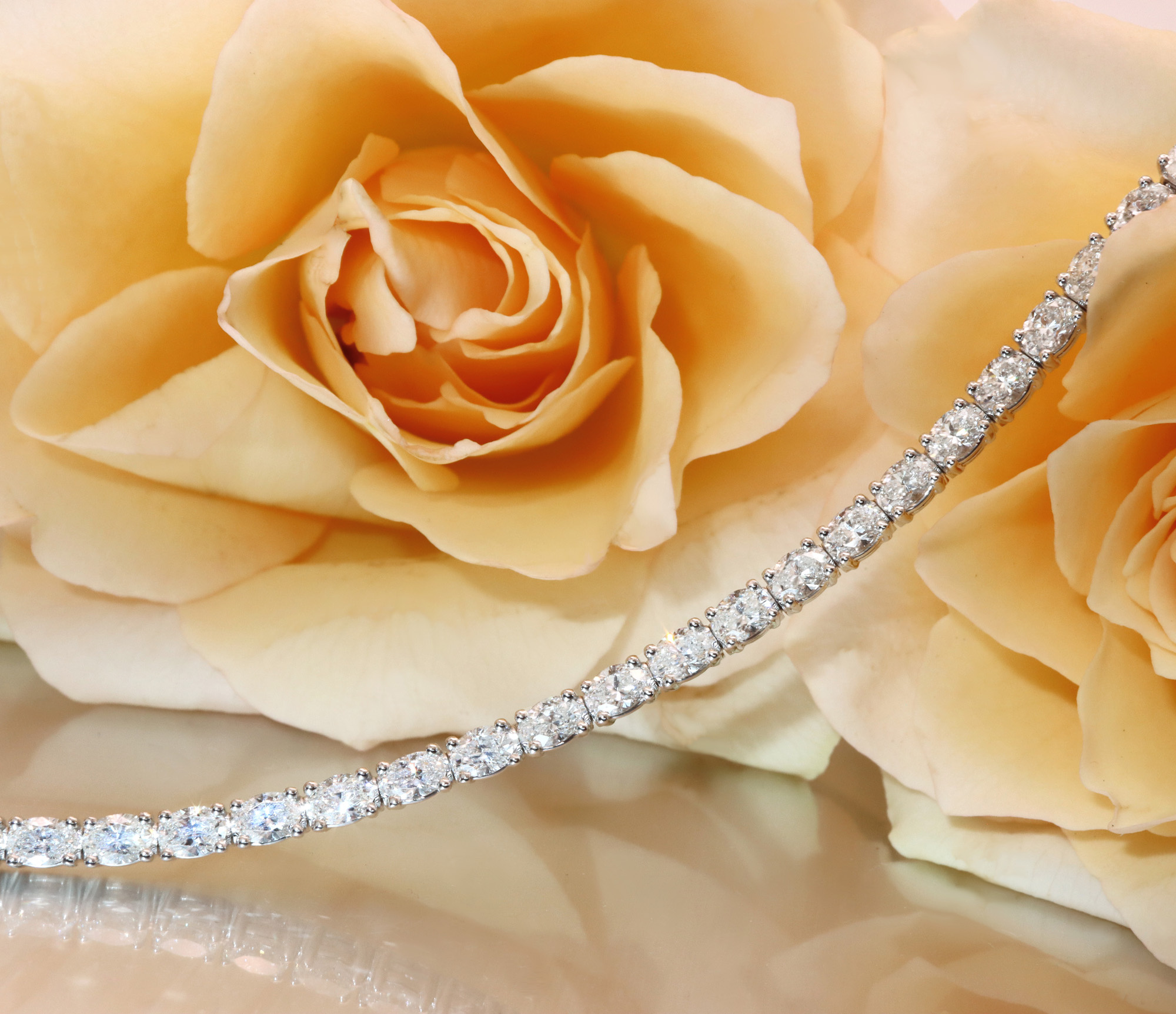 Schlankes Tennisarmband mit ovalen Diamanten auf Rosenblüte