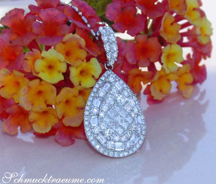 Diamant-Tropfen-Anhänger in Weißgold, detailreich mit Princess- und Baguette-Diamanten, vor Blütenhintergrund.