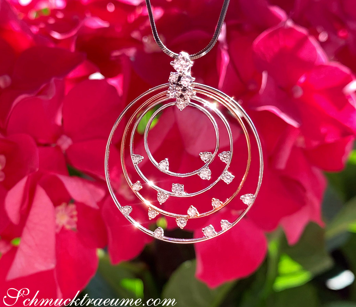 Kreisförmiger Brillantanhänger mit funkelnden Steinen, Detailaufnahme, sanfte Perspektive, vor roten Blüten.