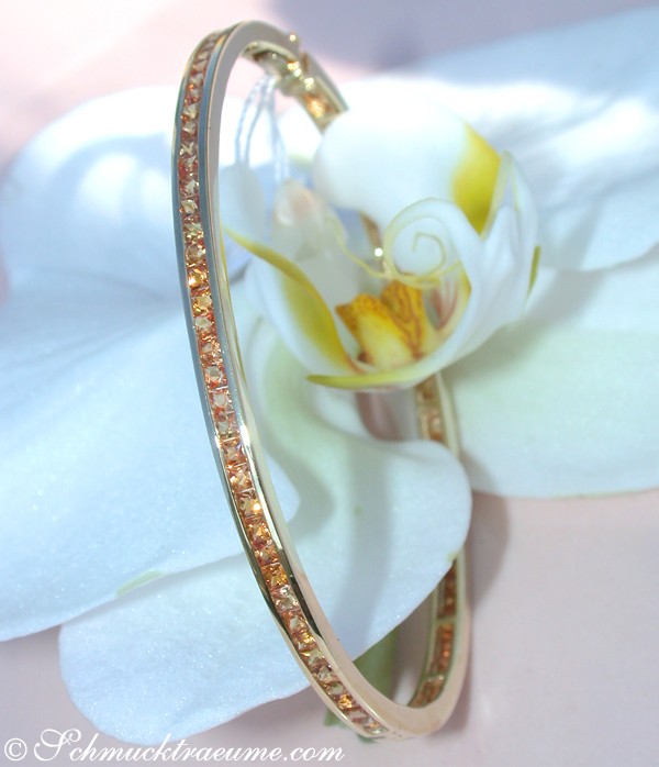 Goldene Armbanddetail mit orangen Saphiren auf Orchidee