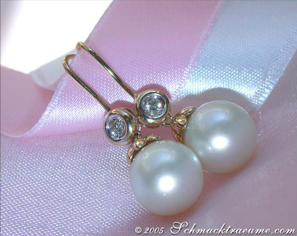 Gelbgold-Ohrhänger mit Südseeperlen und Brillanten auf rosa Seide.