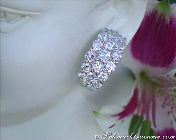 Weißgold-Halbcreolen mit 38 Brillanten, Detailaufnahme, auf weißem Hintergrund, Blume im Hintergrund