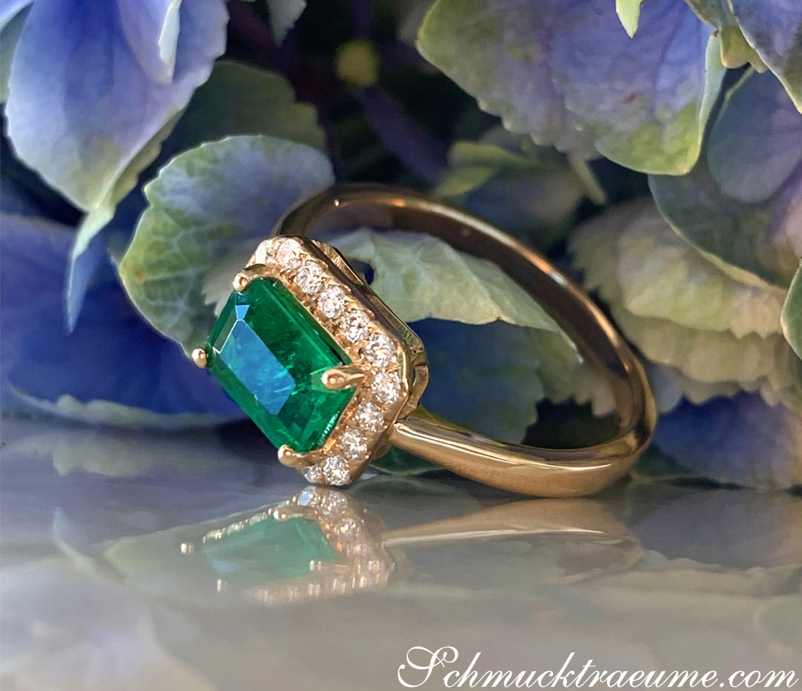 Goldener Smaragd-Ring mit Brillanten, Detailaufnahme, blauer Hintergrund