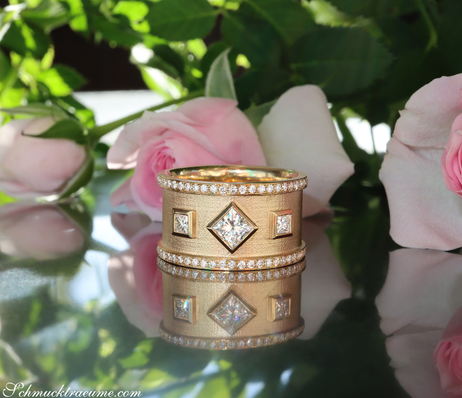 Goldene Diamantringe mit Prinzessenschliff auf Rosenhintergrund