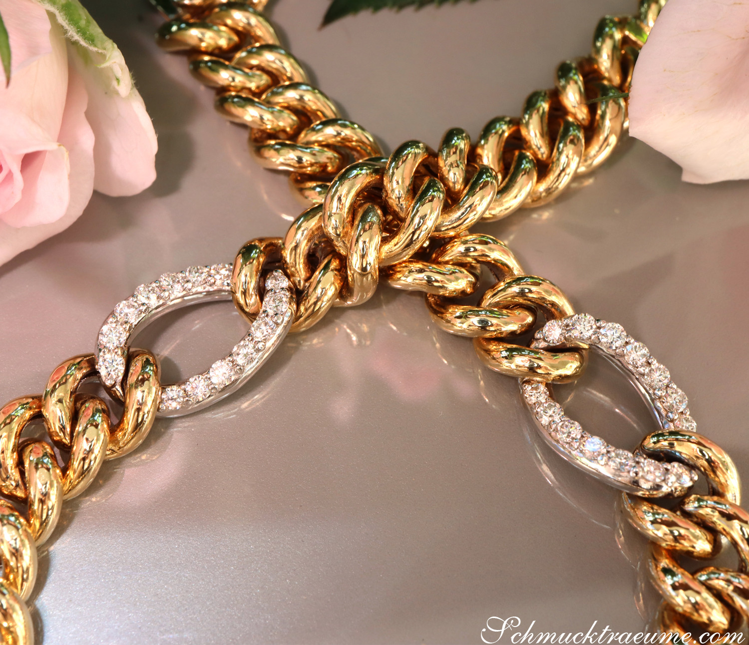 Goldene Panzerarmband mit Brillanten, detailreich, glänzend, rosa Blüte im Hintergrund